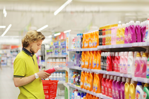 Man shopping in supermarket reading product information.(diapers,detergent)