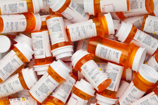 Dozens of prescription medicine bottles in a jumble. This collection of pill bottles is symbolic of the many medications senior adults and chronically ill people take.